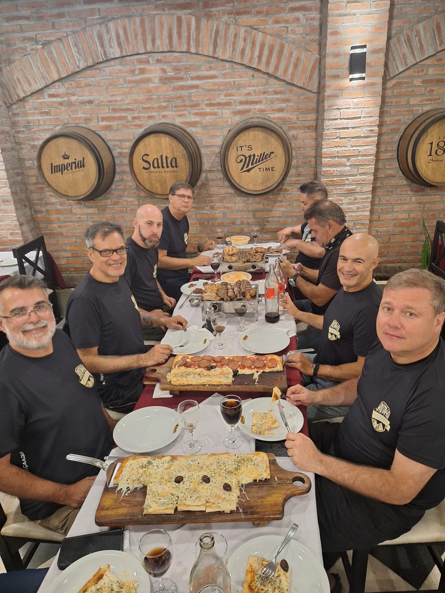 Grupo sorrindo em volta de uma mesa farta, numa selfie tirada de cima